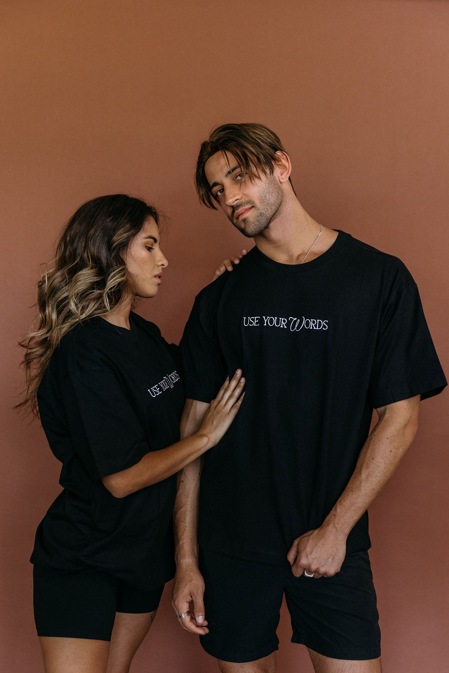 Couple wearing the black "Use Your Words" relaxed fit embroidered T-shirt by WNGSPN, styled as elevated romance reader apparel.