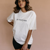Female model wearing the ecru "Use Your Words" relaxed fit embroidered T-shirt by WNGSPN, styled in a minimal, elevated aesthetic.