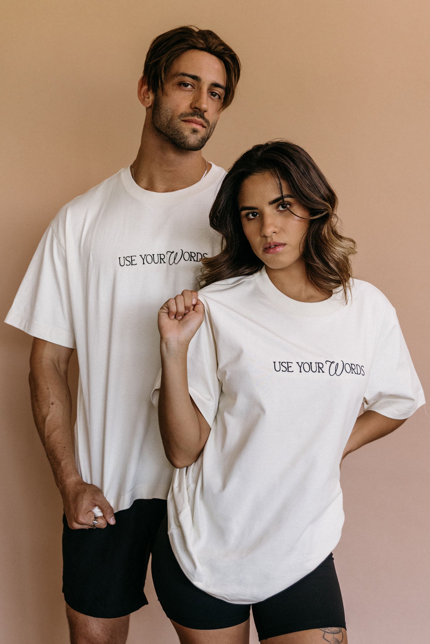 Couple wearing the ecru "Use Your Words" relaxed fit embroidered T-shirt by WNGSPN, capturing a refined bookish aesthetic.