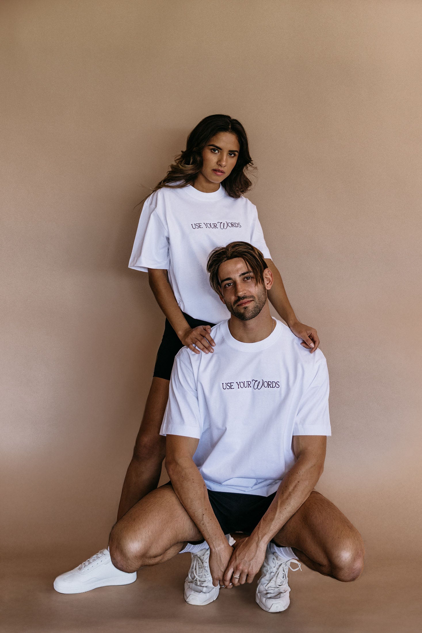 Couple wearing the white "Use Your Words" relaxed fit embroidered T-shirt by WNGSPN, with subtle tension and modern edge.