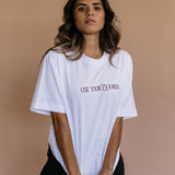 Female model wearing the white "Use Your Words" relaxed fit embroidered T-shirt by WNGSPN, with a relaxed silhouette and clean lines.