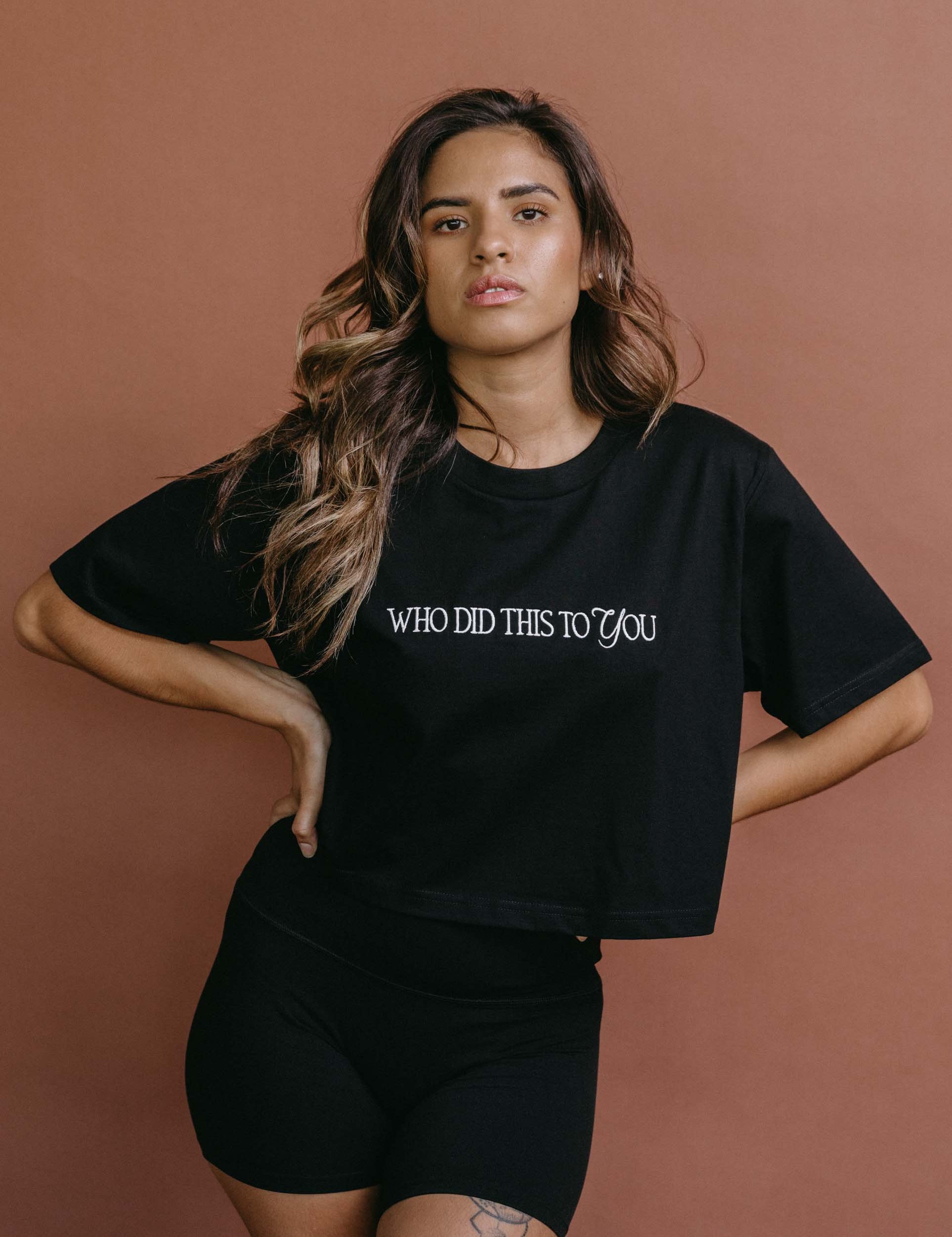 Female model wearing the black "Who Did This To You" cropped embroidered T-shirt by WNGSPN, with a relaxed silhouette and clean lines.