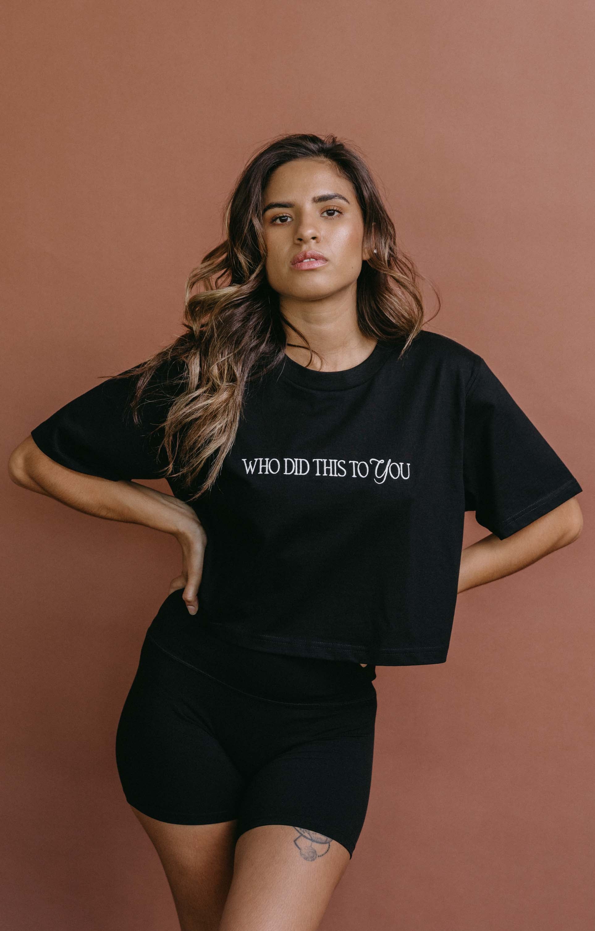 Female model wearing the black "Who Did This To You" cropped embroidered T-shirt by WNGSPN, with a relaxed silhouette and clean lines.