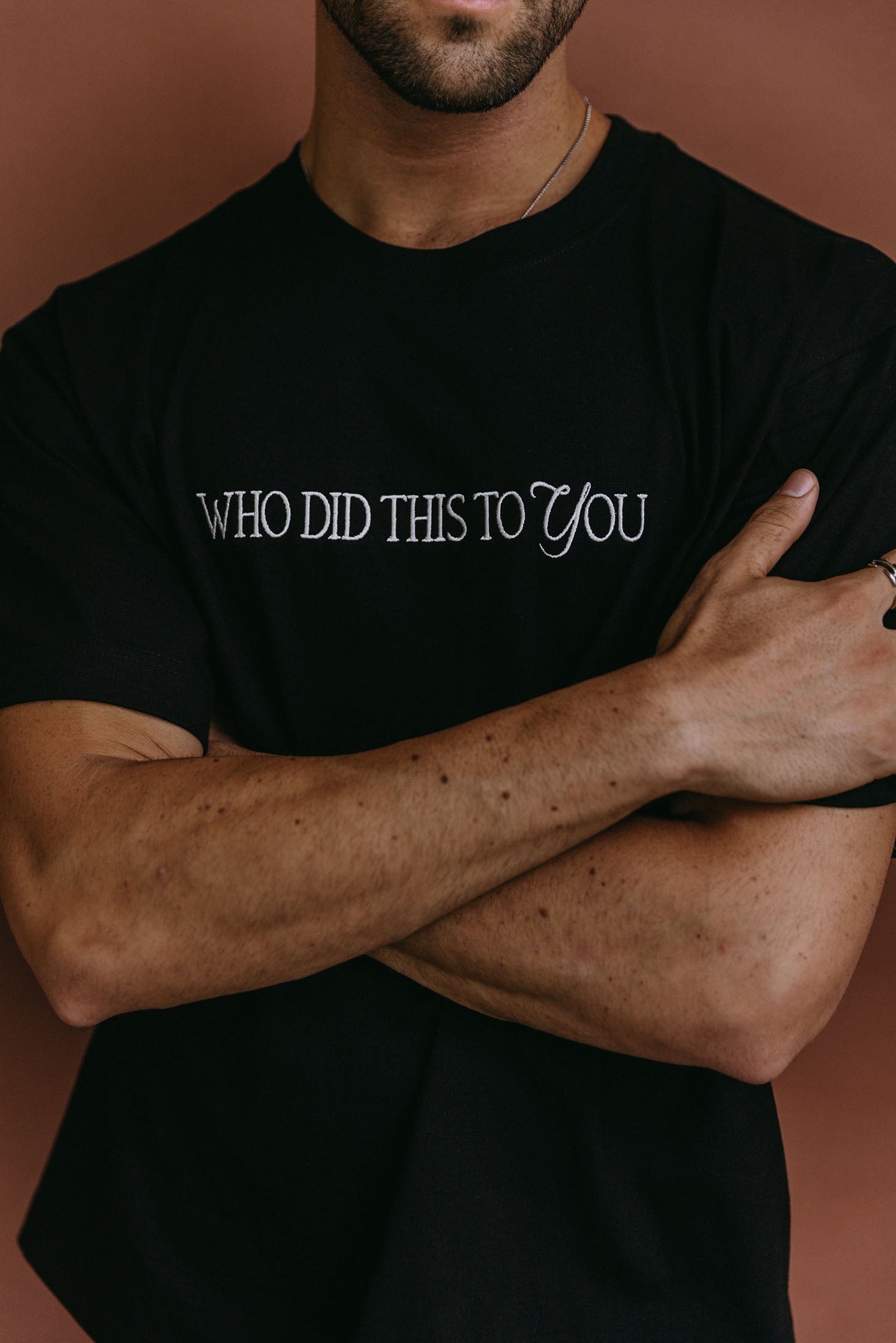 Close-up embroidery detail of the "Who Did This To You" relaxed fit T-shirt by WNGSPN, highlighting clean, minimalist embroidery.