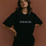 Female model wearing the black "Who Did This To You" relaxed fit embroidered T-shirt by WNGSPN, styled with understated confidence.