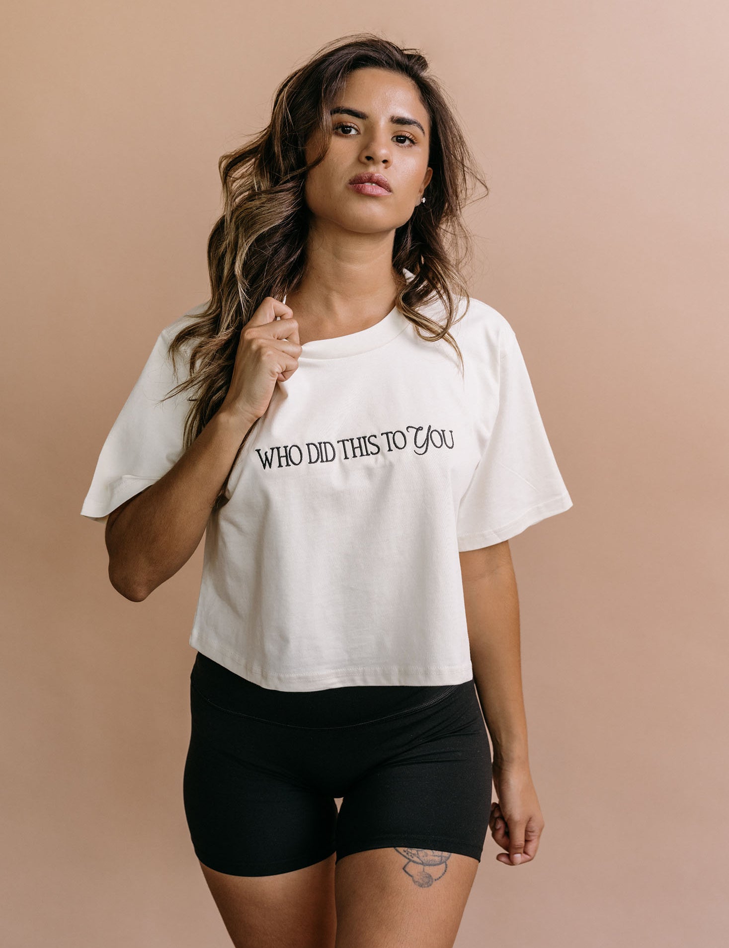 Female model wearing the ecru "Who Did This To You" cropped embroidered T-shirt by WNGSPN, with a relaxed silhouette and clean lines.