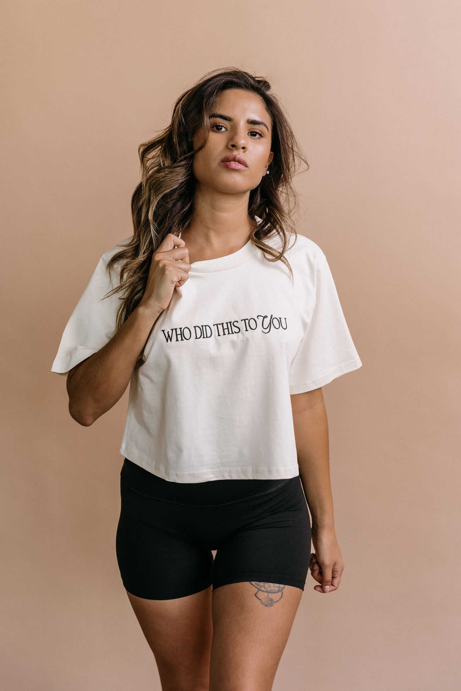 Female model wearing the ecru "Who Did This To You" cropped embroidered T-shirt by WNGSPN, with a relaxed silhouette and clean lines.