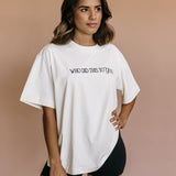 Female model wearing the ecru "Who Did This To You" relaxed fit embroidered T-shirt by WNGSPN, styled in a minimal, elevated aesthetic.