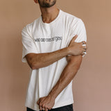 Male model wearing the ecru "Who Did This To You" relaxed fit embroidered T-shirt by WNGSPN, styled in a minimal, elevated aesthetic.
